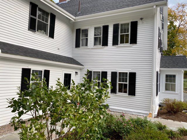 A large white house with black shutters and a black roof.
