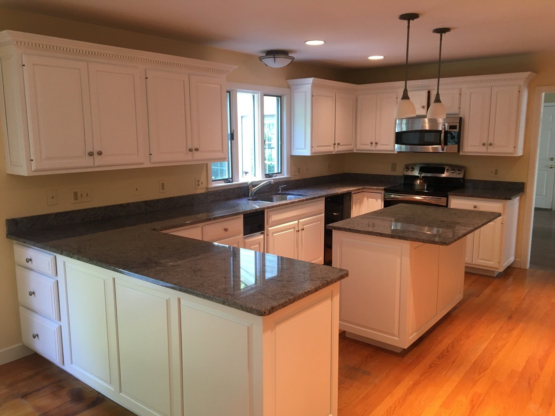 A kitchen with white cabinets and granite counter tops