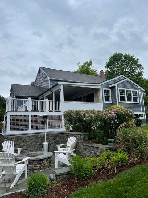 A house with a large deck and chairs in front of it.