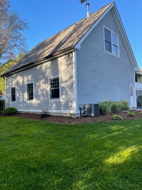 A white house with a brown roof and a lot of windows