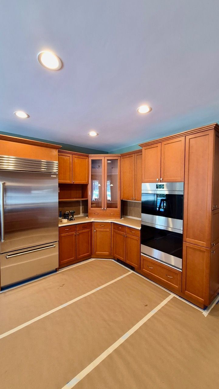 Kitchen with honey-toned wood cabinets before professional cabinet painting in Medfield MA by Laperle Painting