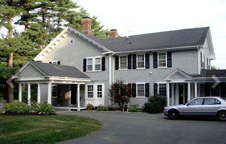 A white car is parked in front of a large house