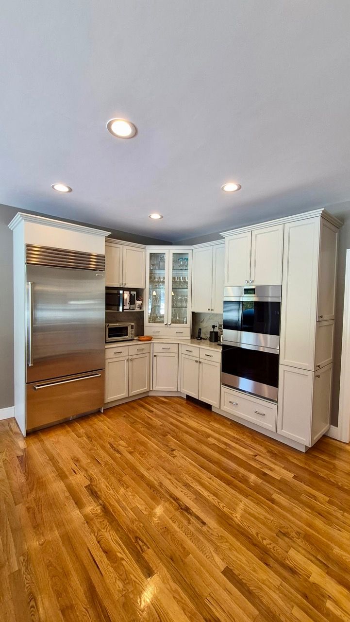White painted kitchen cabinets with marble backsplash and stainless steel range after professional cabinet painting in Medfield MA