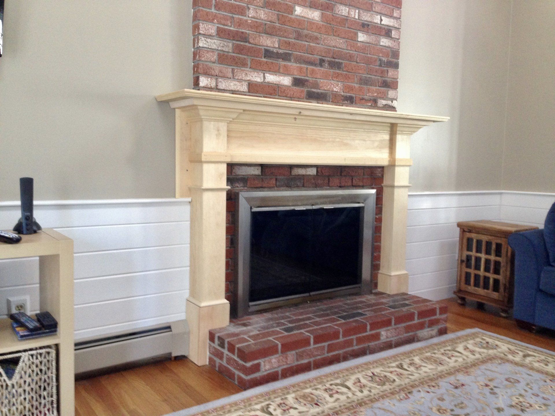 A living room with a brick fireplace and a new wooden mantle