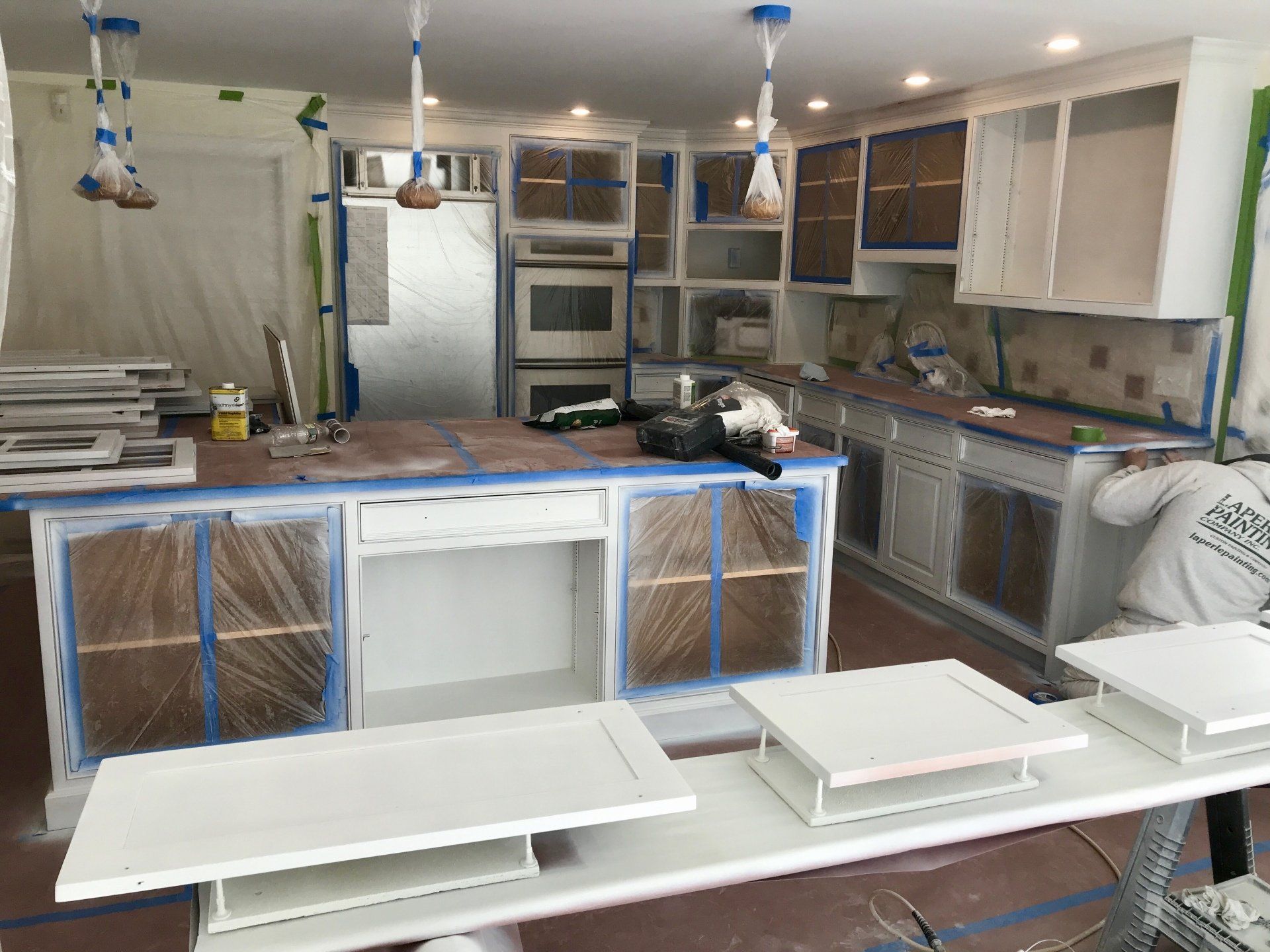 A kitchen with a lot of cabinets being painted