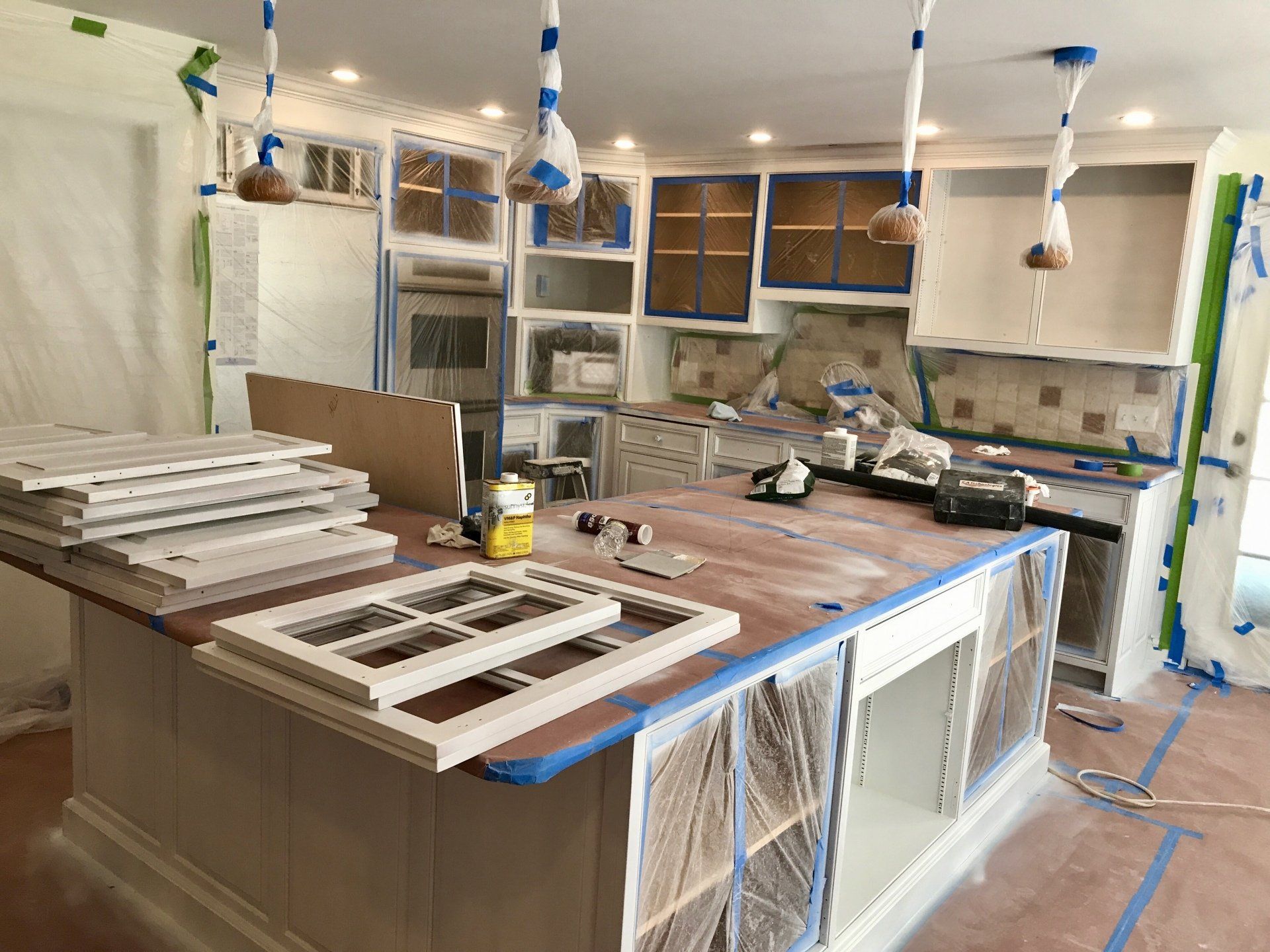 A kitchen is being remodeled and the cabinets are being painted.