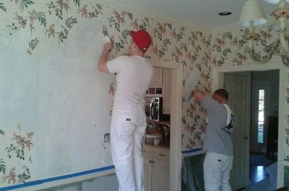 Men removing wallpaper from indoor room