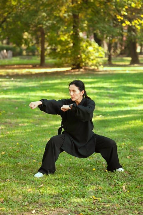 A woman is practicing martial arts in a park.