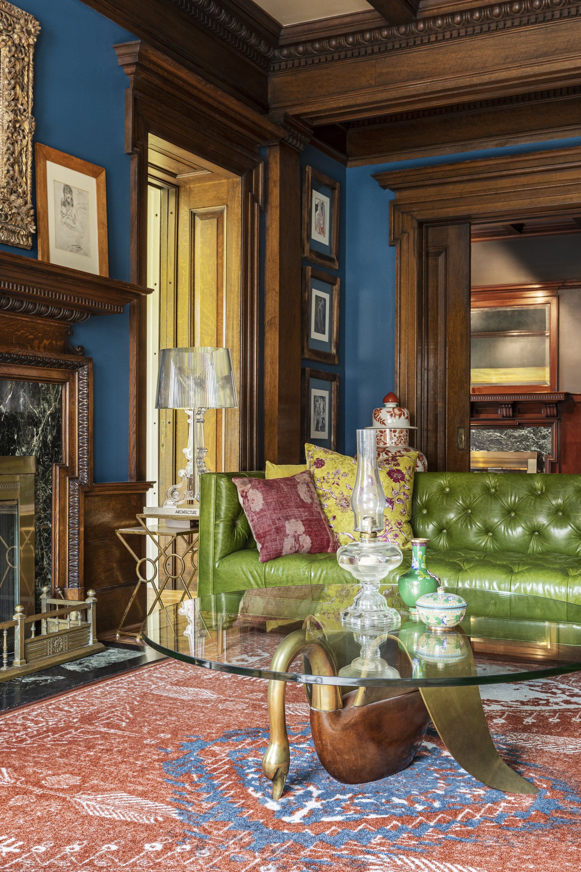 A living room featuring elaborate oak millwork and jewel tones with eclectic furnishings focused around a large fireplace.