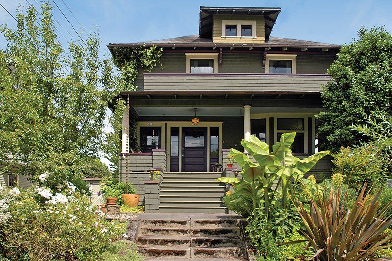 Picture of the front of a 1908 Shingle Style Foursquare home on a sunny day.