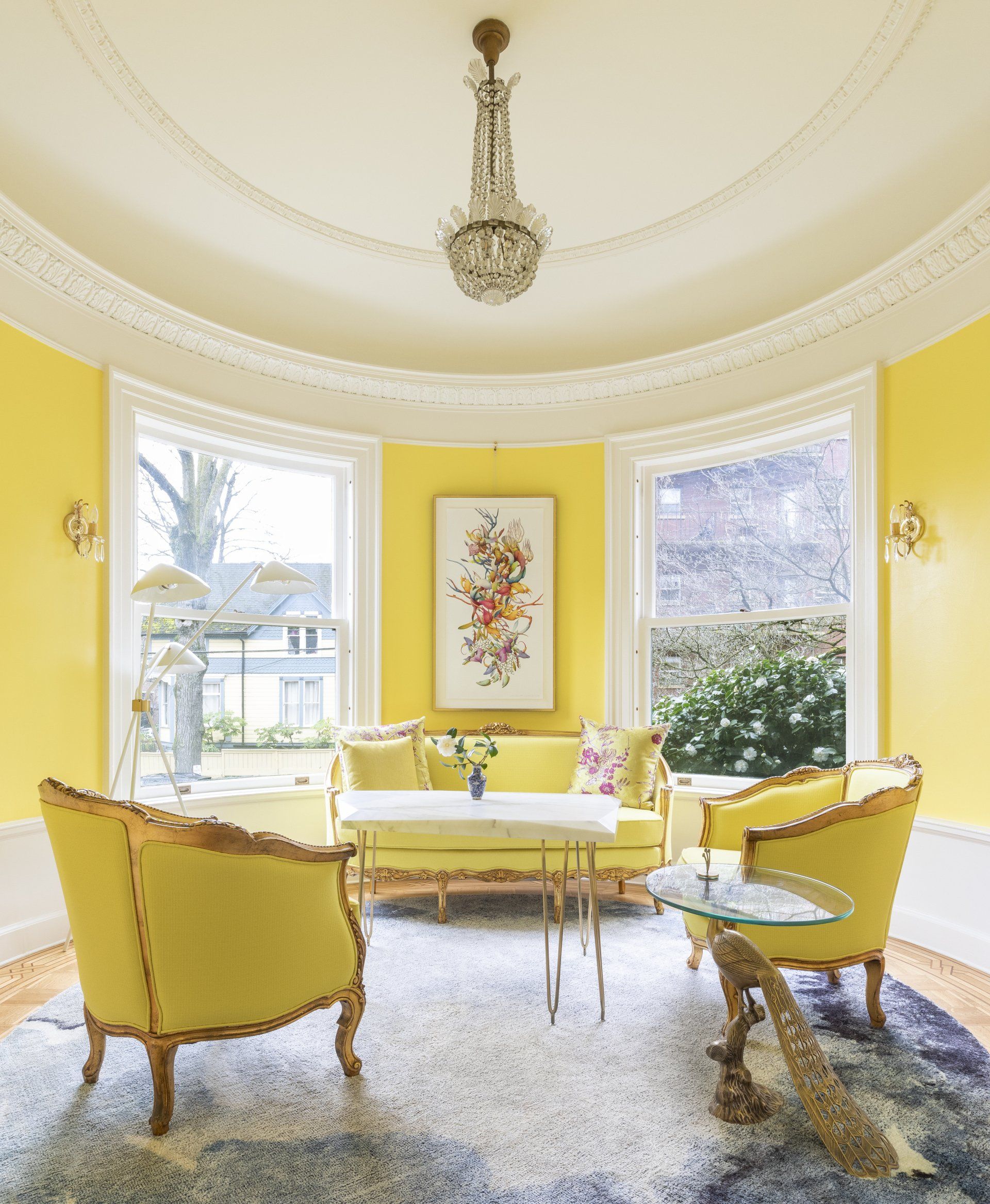 A round room with domed ceiling, elaborate millwork, bright yellow walls and furnishings, and a painting by Miron Schmueckle.