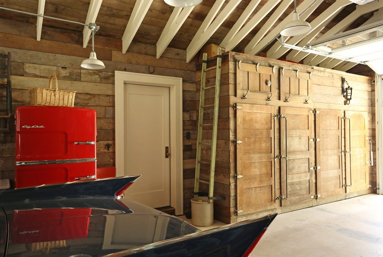 Inside the new garage, salvaged refrigerator doors and shiplap paneling contrast with white scissor truss system.