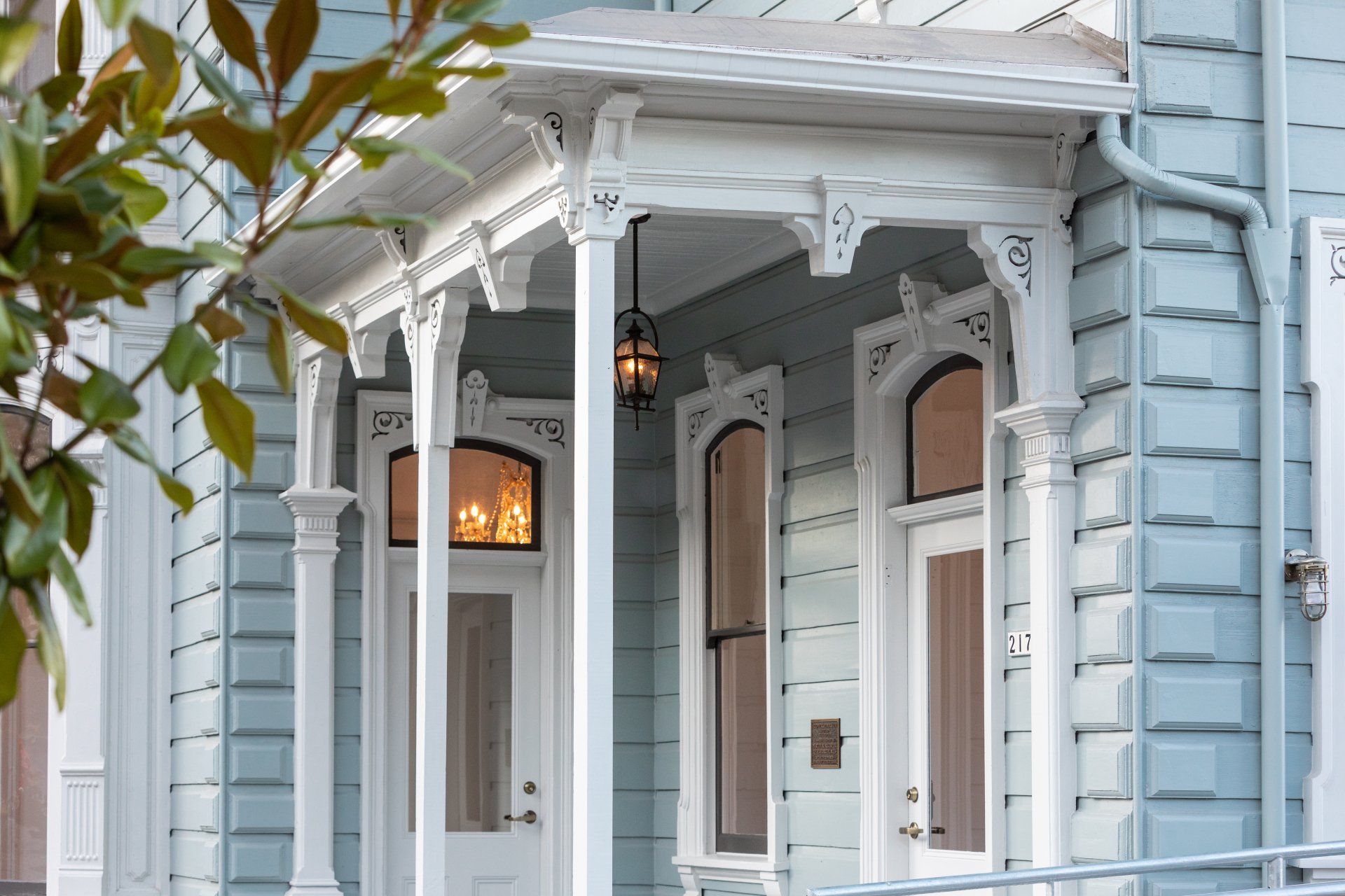 Italianate details include tall, narrow double hung windows with split arched tops and quoining at the corners of the house.