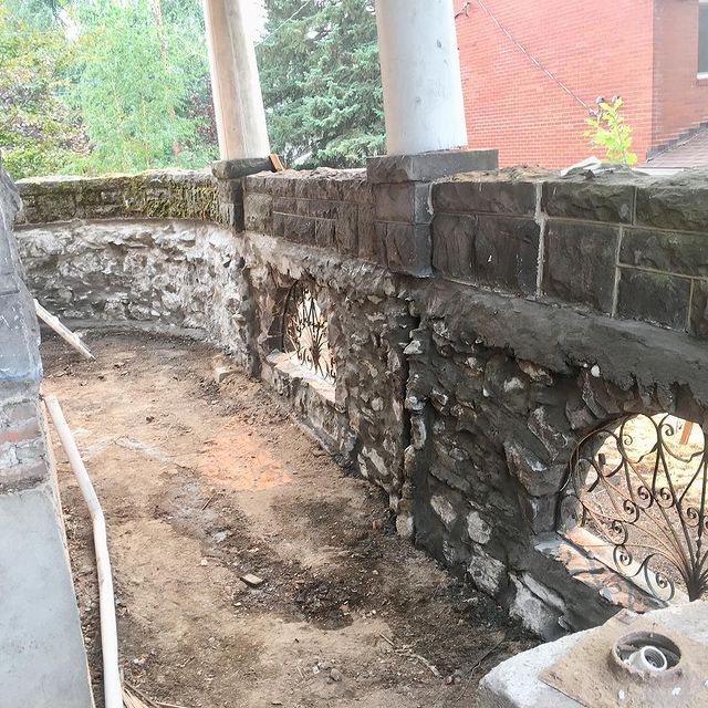 A stone wall with a window in the middle of it