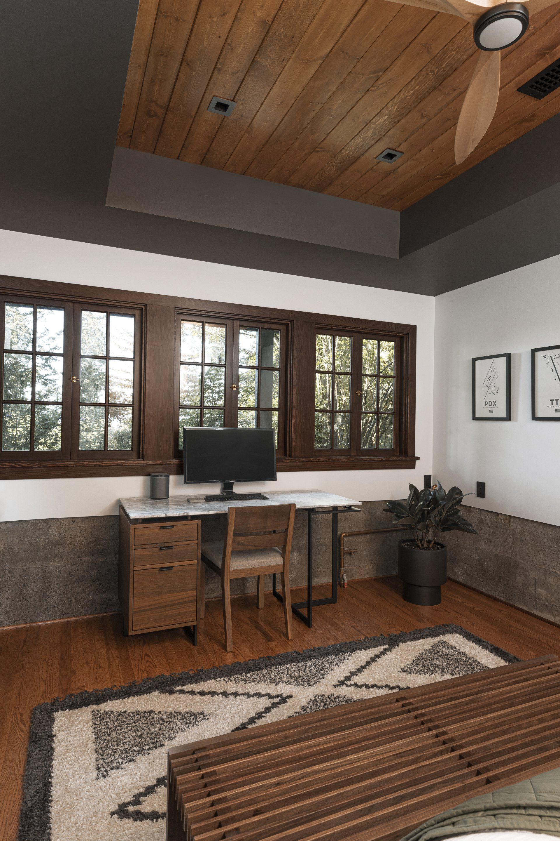 A room with a desk , chair , computer and a ceiling fan.