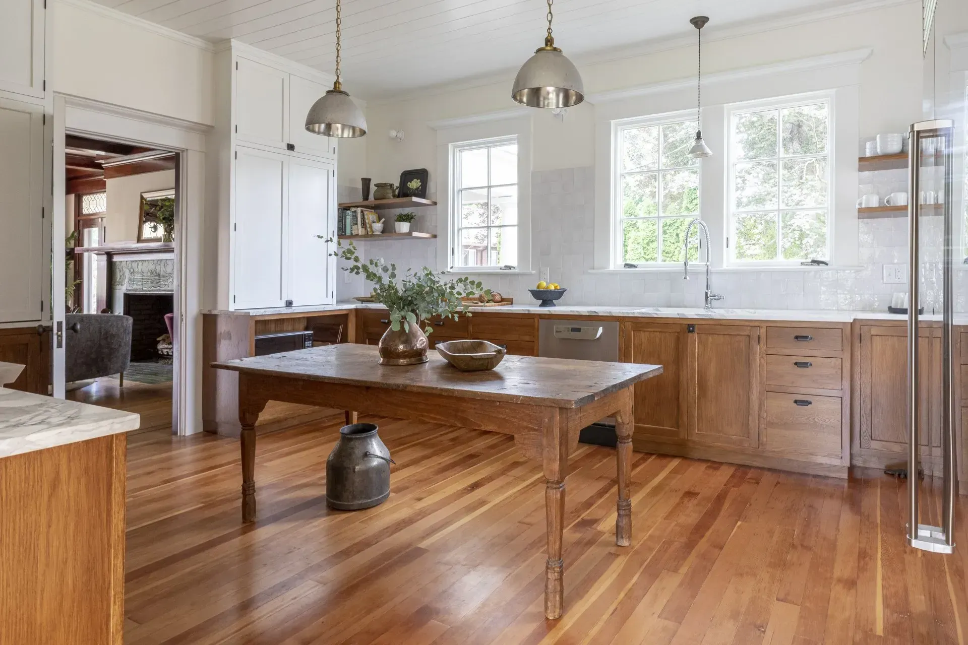 A kitchen with wooden cabinets , hardwood floors and a wooden table.