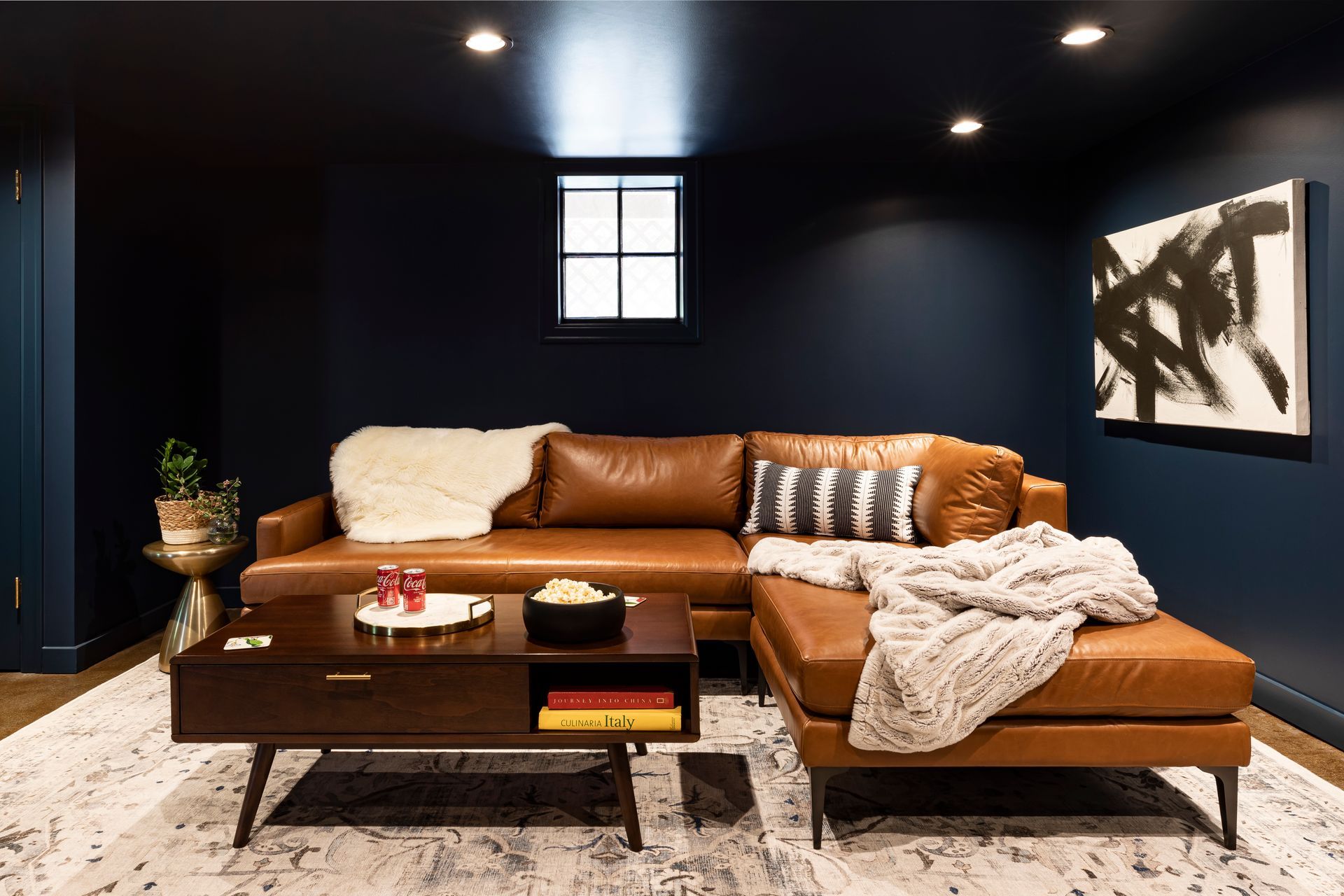 Remodeled basement lounge area with dark blue walls and ceiling and polished concrete floors.