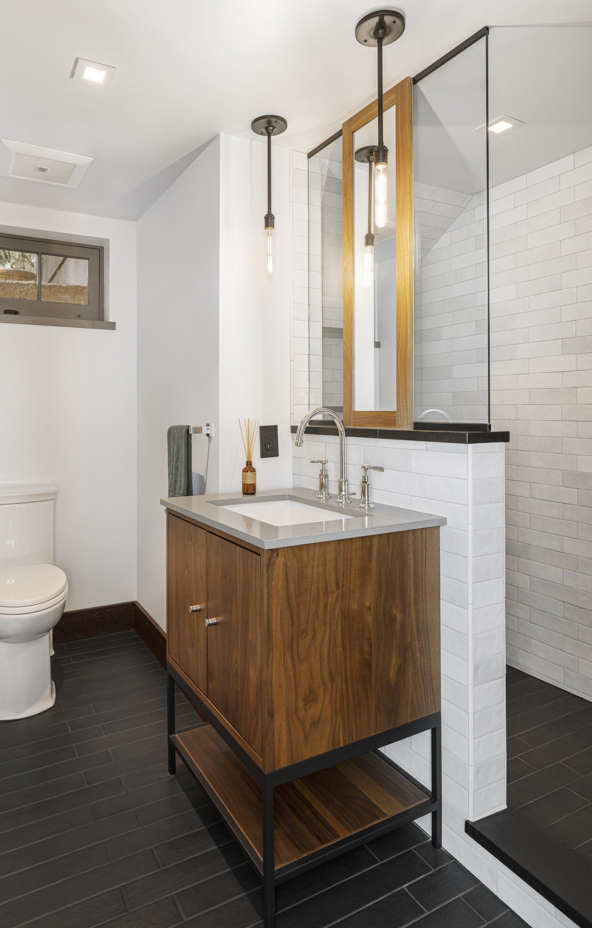 In the basement, the guest bathroom's shower is tucked behind a pony wall which allows some privacy but also lets light in