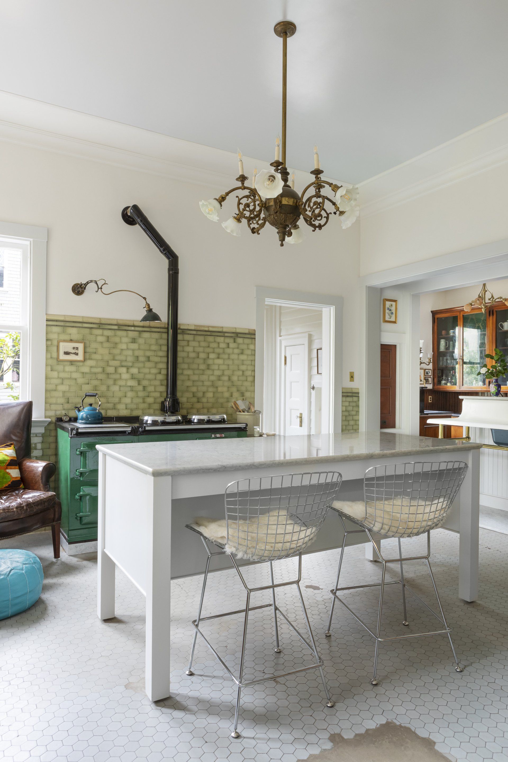 Eclectic kitchen remodel with original wall and floor tile, green vintage Aga range, custom island by Arciform, and salvaged chandelier.