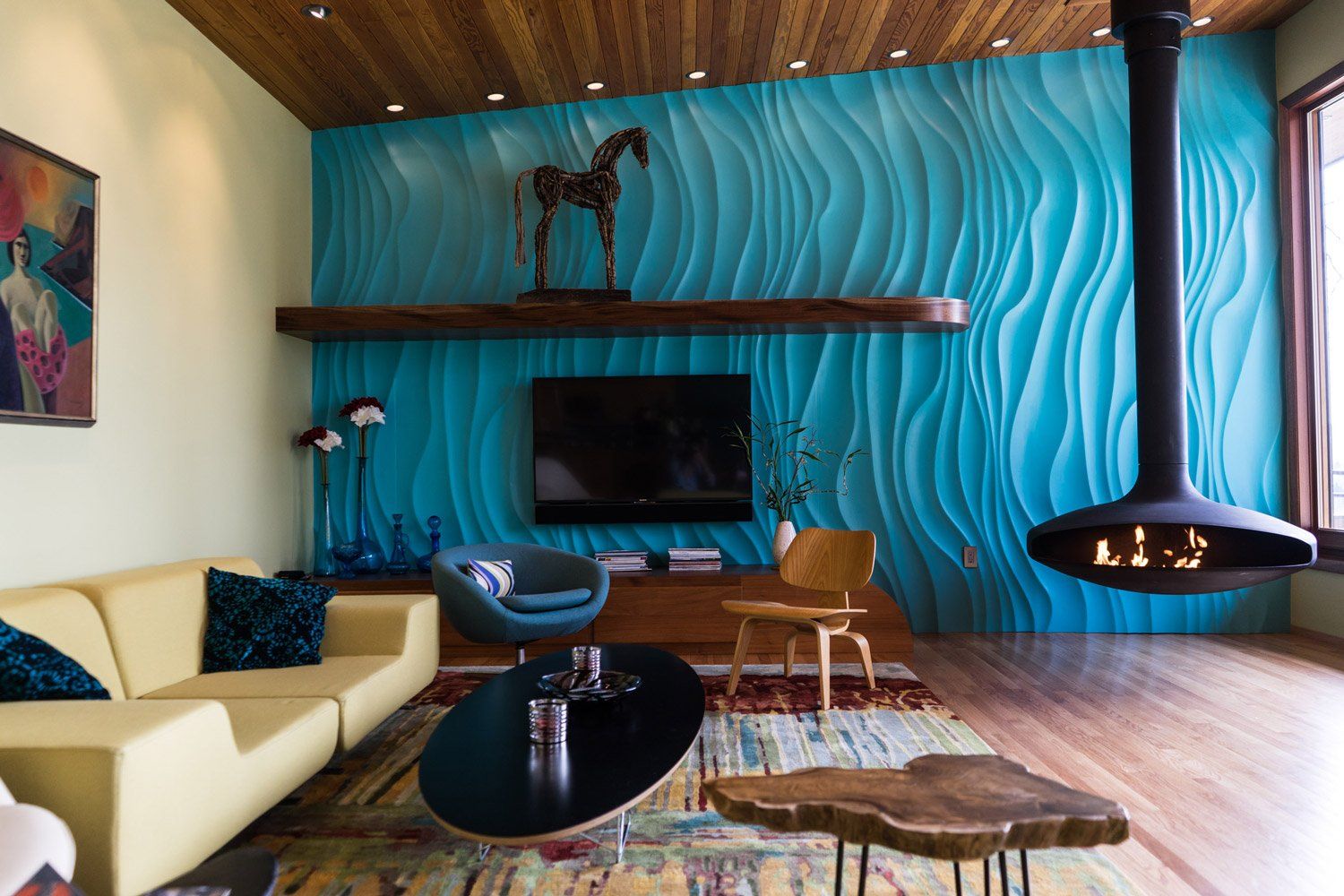 A turquoise, undulating wall is set off by custom walnut built-ins & a fir ceiling in the living room.