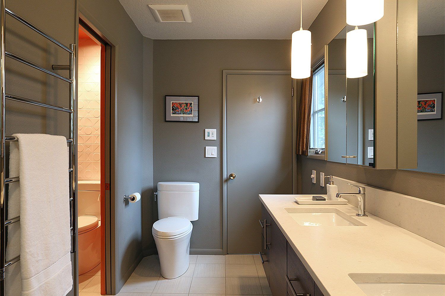 Two baths were combined into the spa-like main bath in cool grays with a poppy white and clementine WC