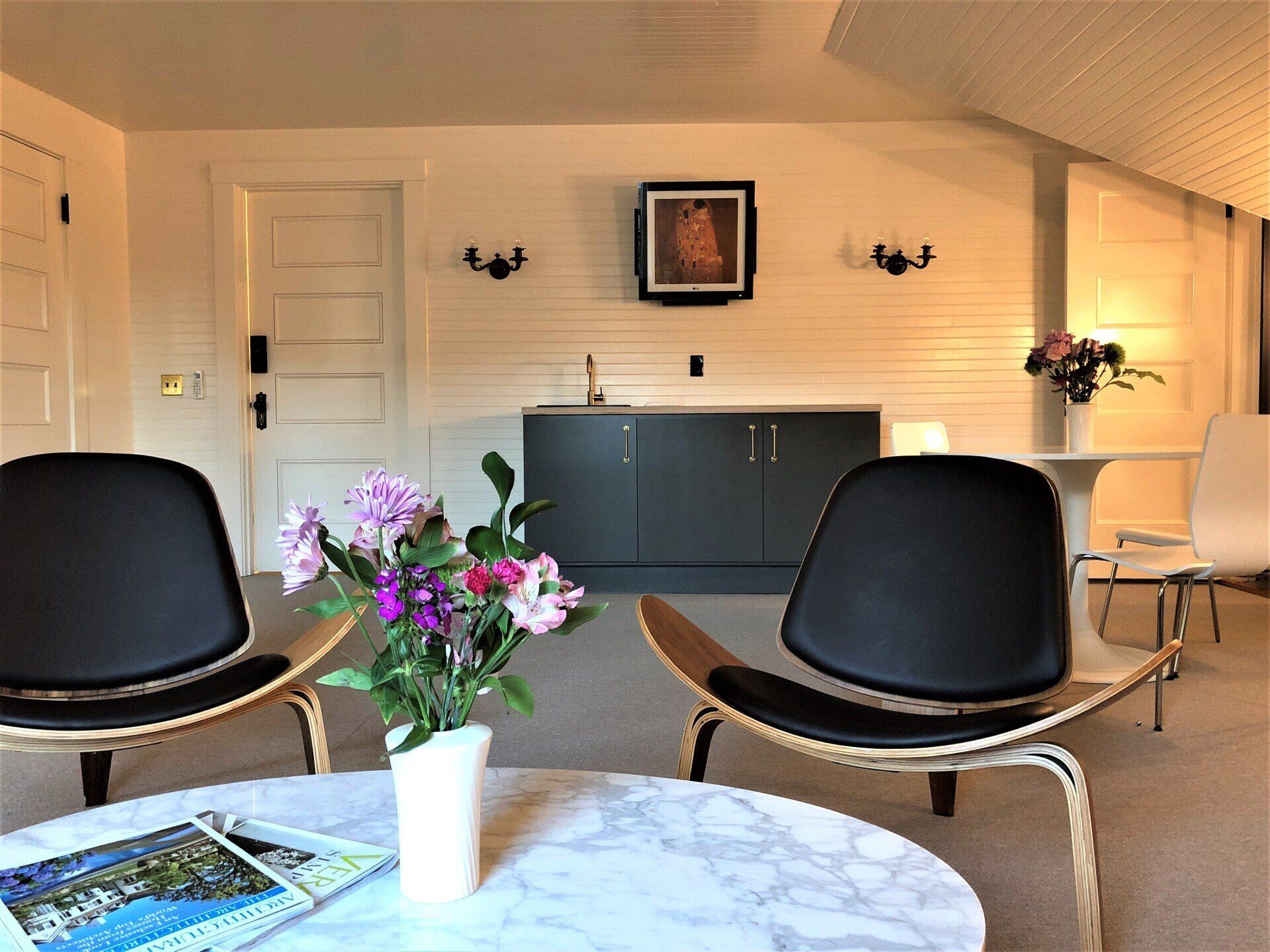 A living room with two chairs and a table with a vase of flowers on it