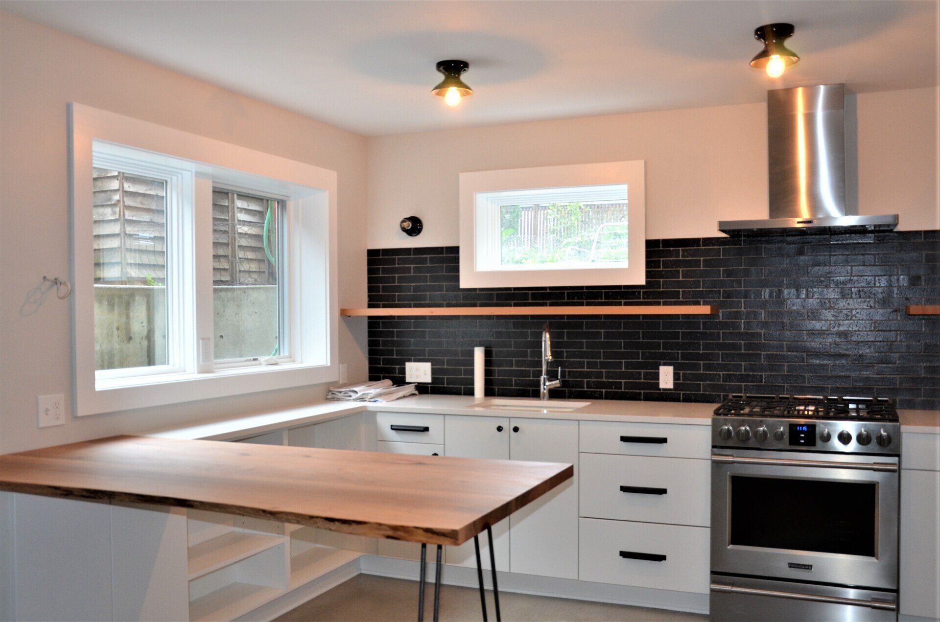 A kitchen with white cabinets , stainless steel appliances and a wooden counter top.