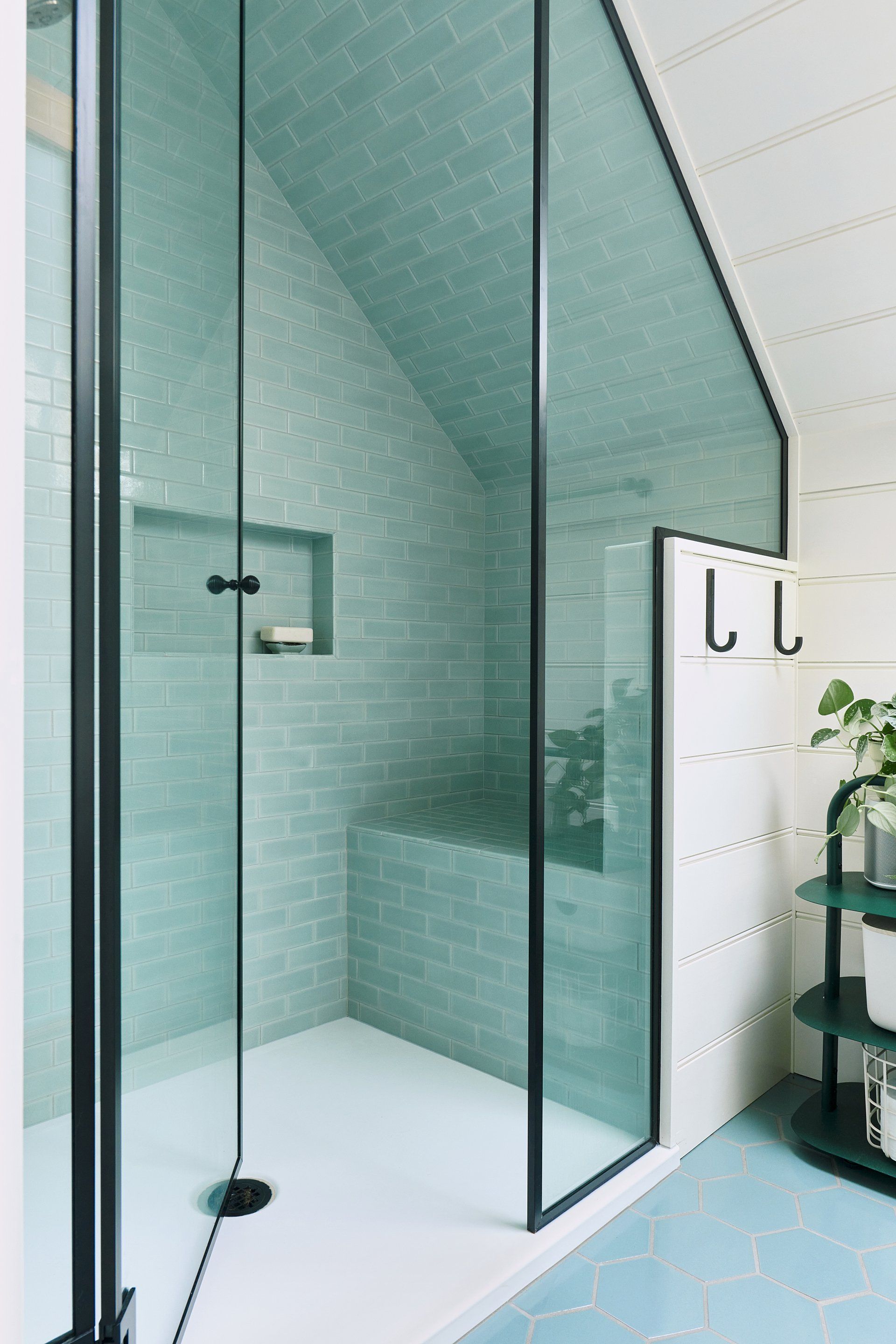 The 2nd floor bath has a roomy shower tiled in ocean hues with a smart under-eave shower bench.