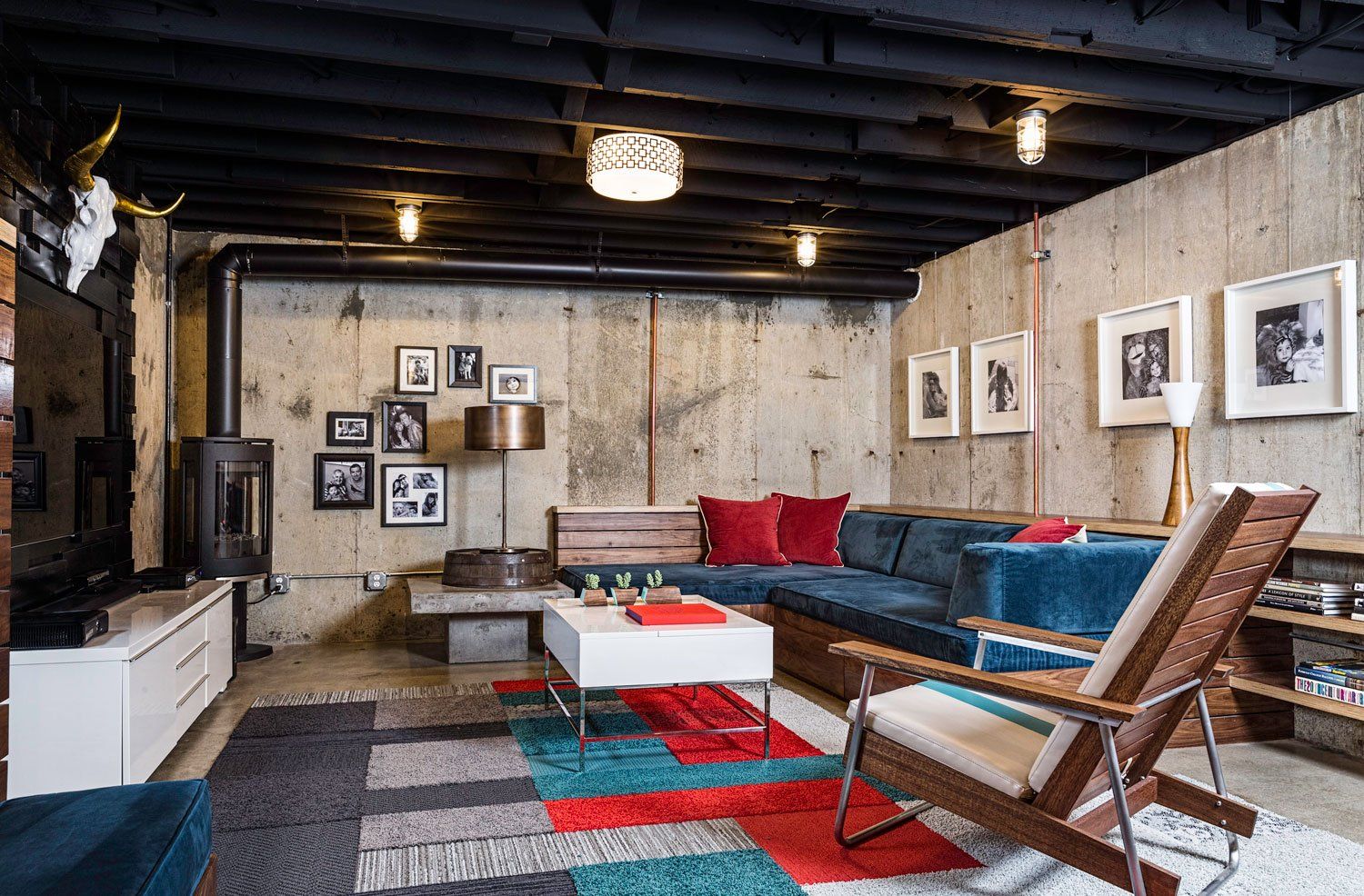 A roomy basement family room with  custom, plush sectional sofa, colorful carpet tile and new corner fireplace.