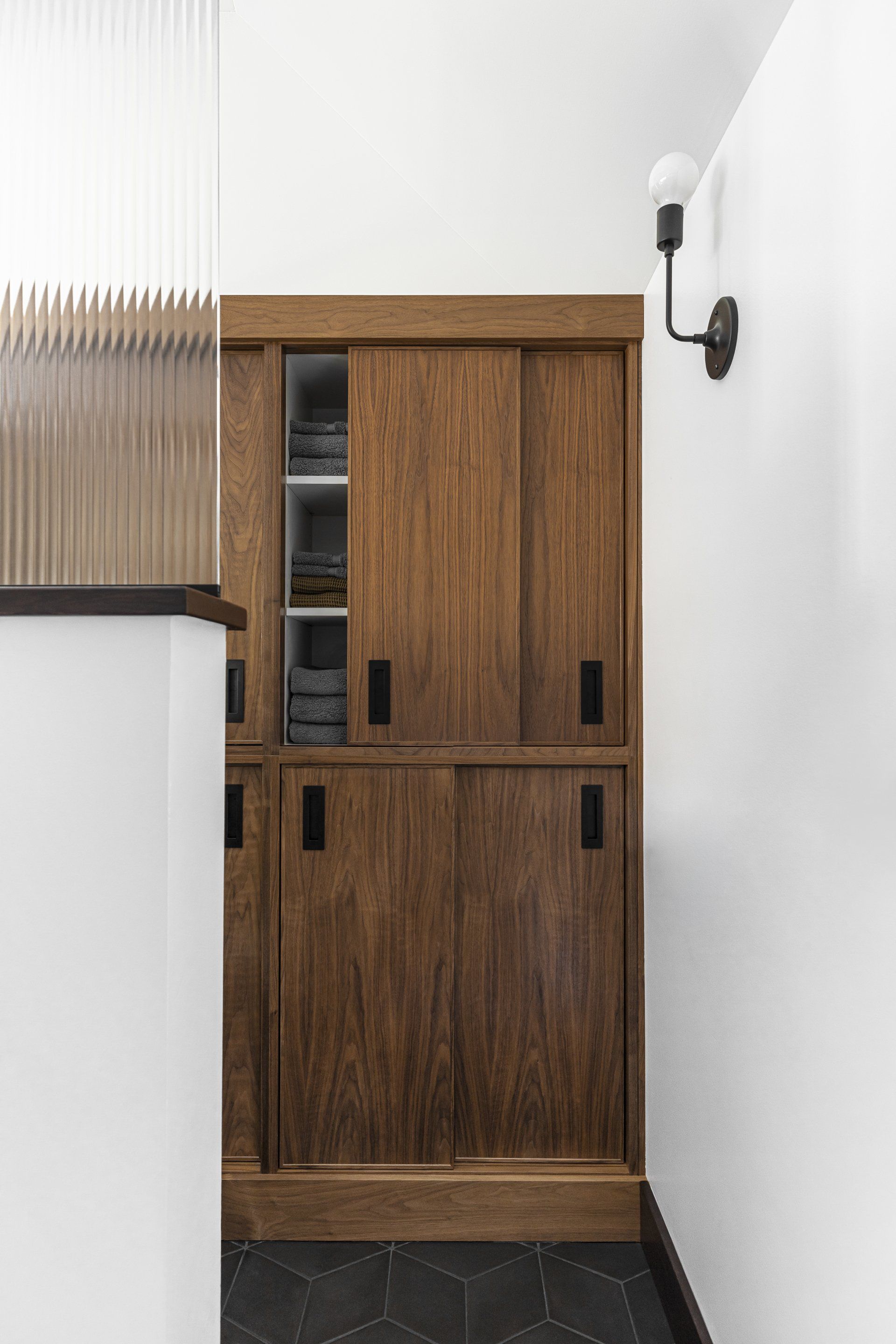 Adjacent to the WC, custom walnut cabinets slide open