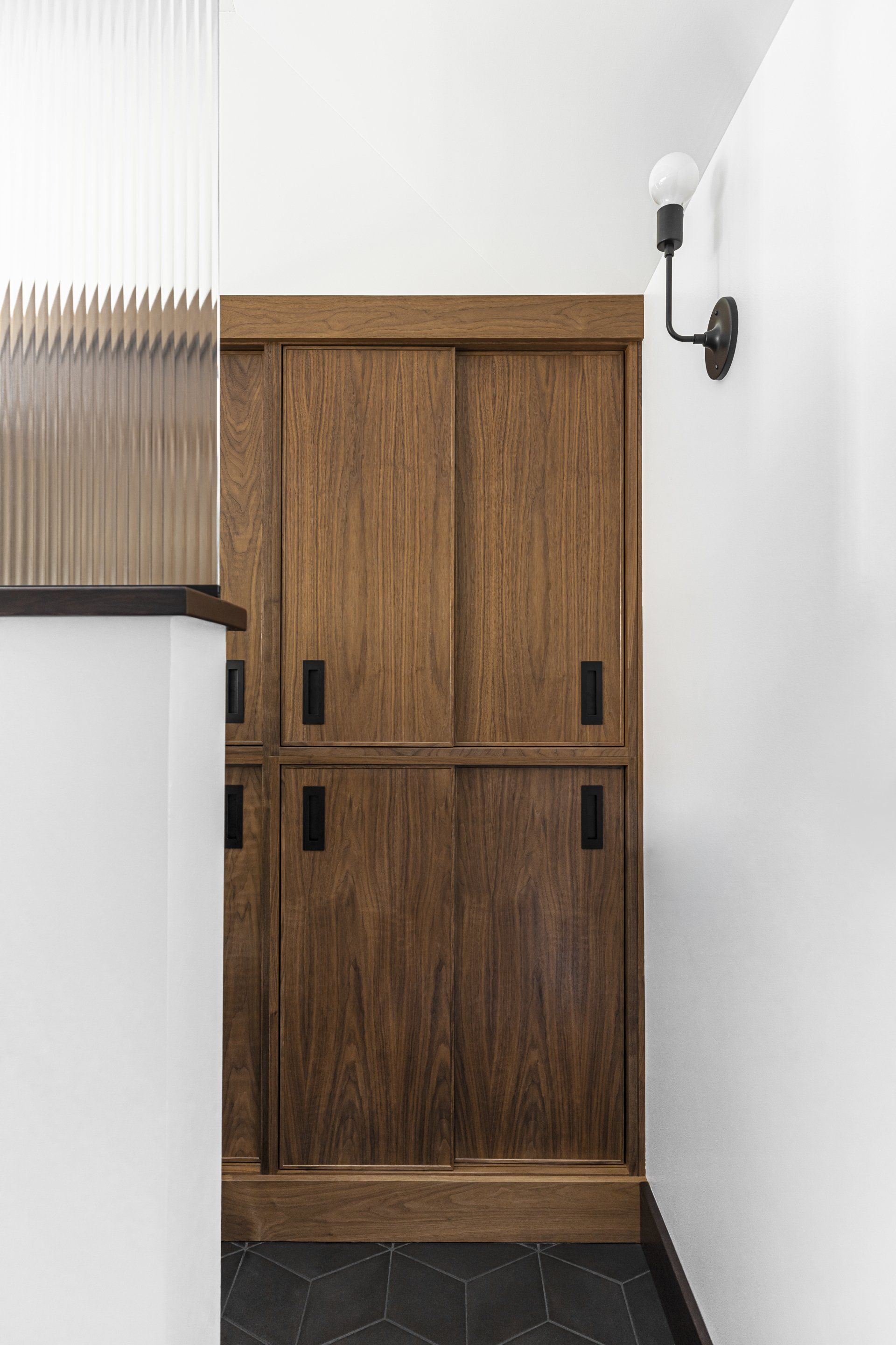 Adjacent to the WC, custom walnut cabinets slide closed