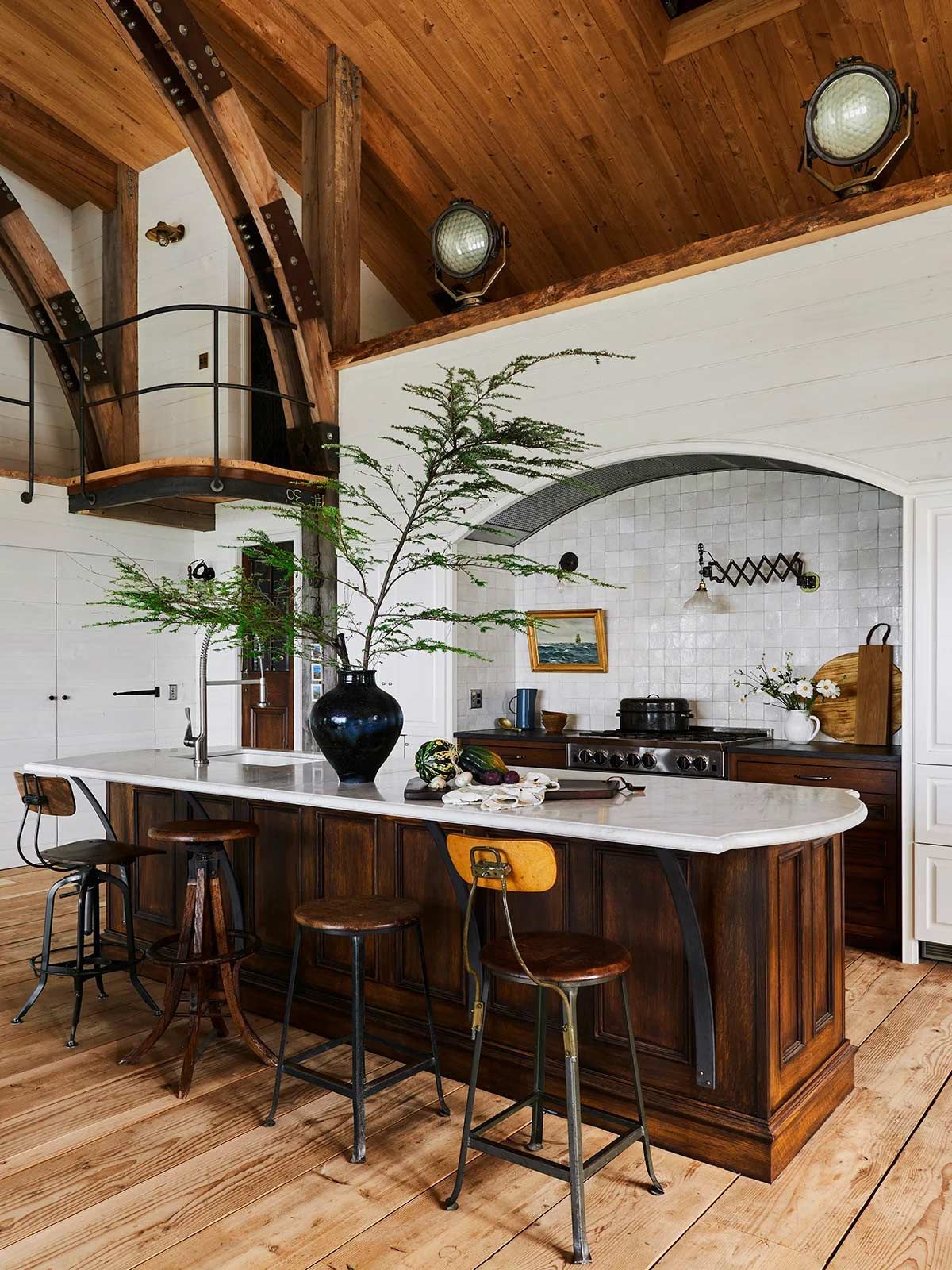 A kitchen with a large island , stools and a stove.
