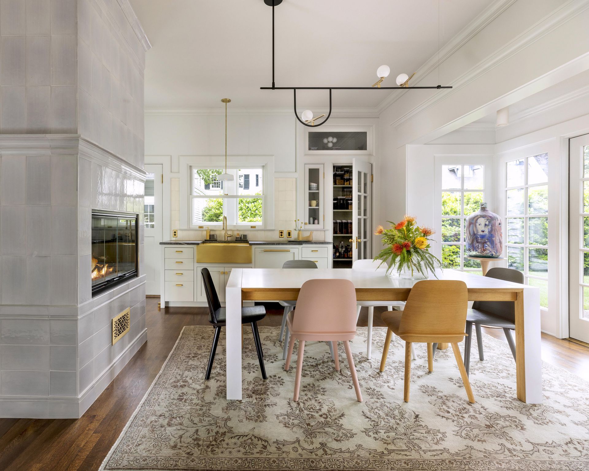 A casual dining area with doors to the yard include a tiled, double sided gas fireplace, a dishwashing area and a small pantry.
