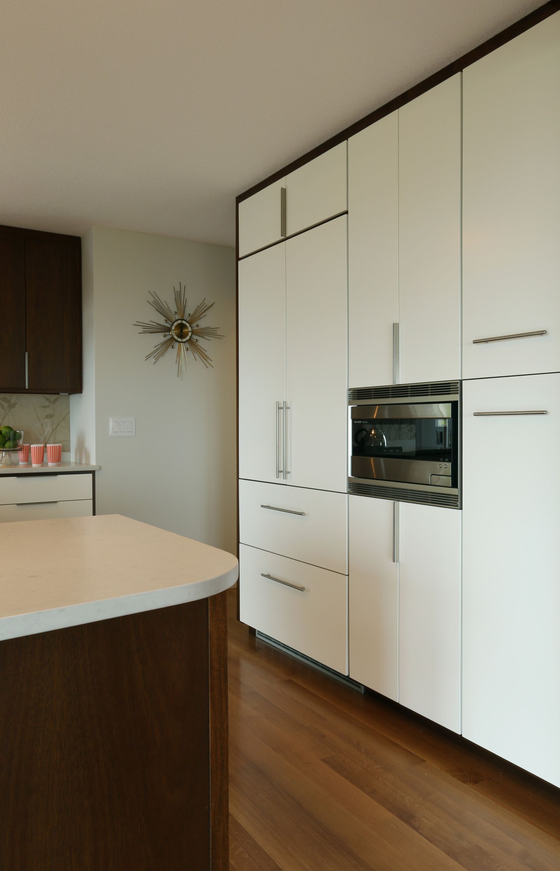 A full height wall of modern white kitchen cabinets offer plenty of storage