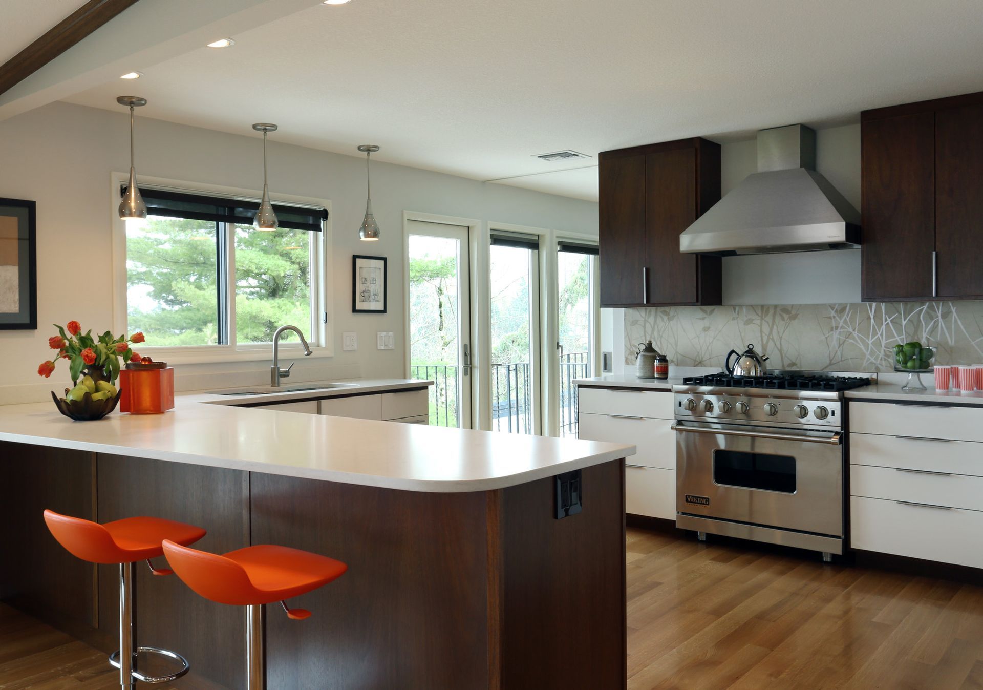 Looking into the kitchen from beyond the island with a view of the range wall, windows and doors to the back of the house