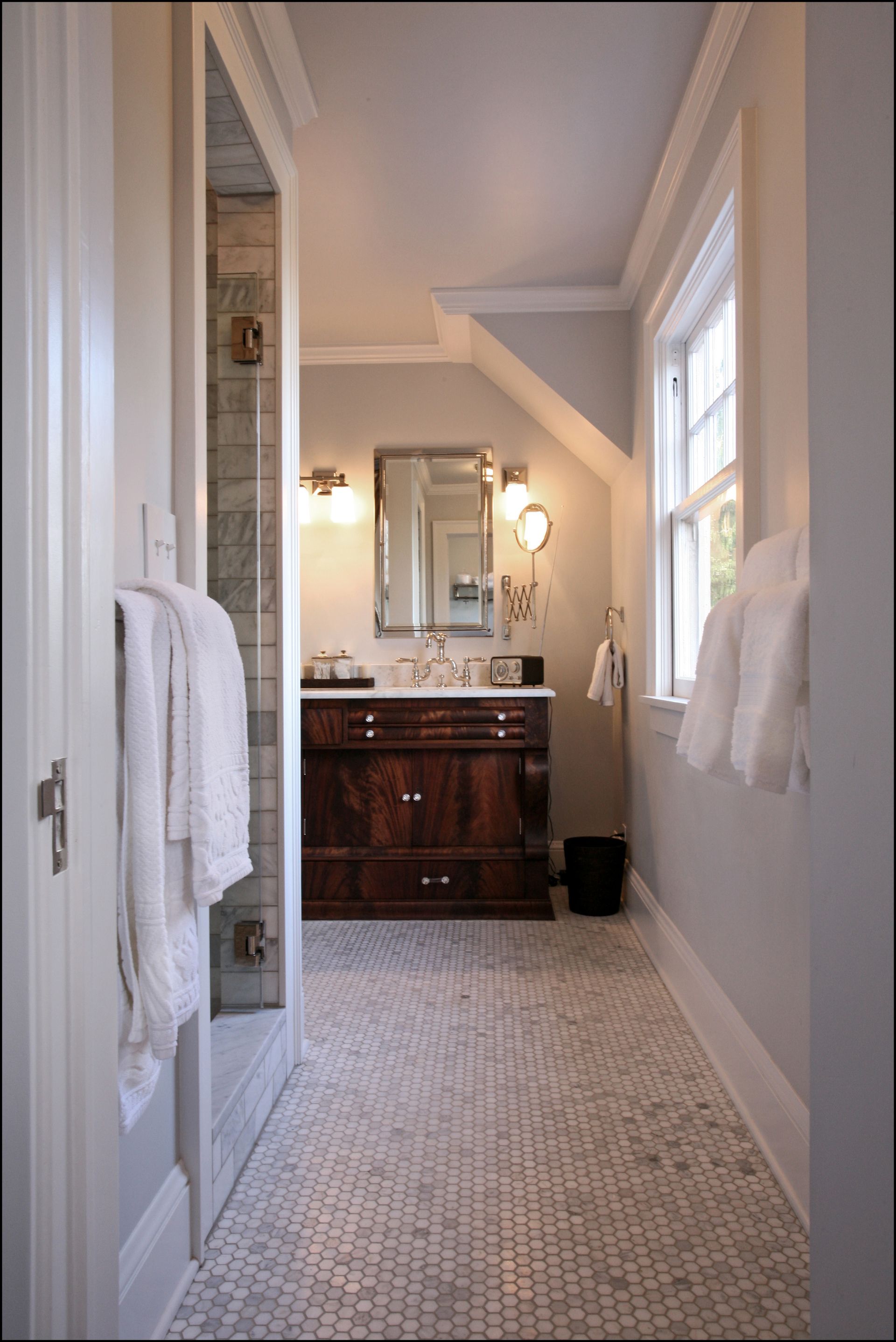 View of the deep-stained vanity  with the marble-tiled shower on the left in the main bath