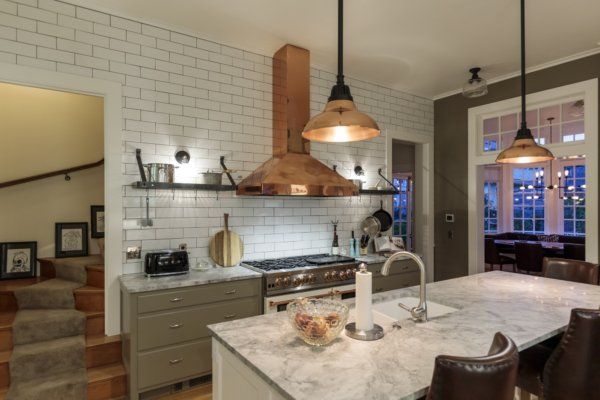 A copper hood and quartzite countertops combine with bold lighting to help anchor the kitchen as both cooking and gathering space.
