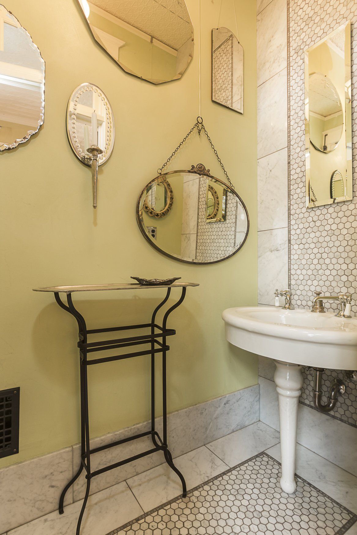 Off the kitchen, the WC has a wall of antique mirrors, dramatic tile and pale yellow green walls.