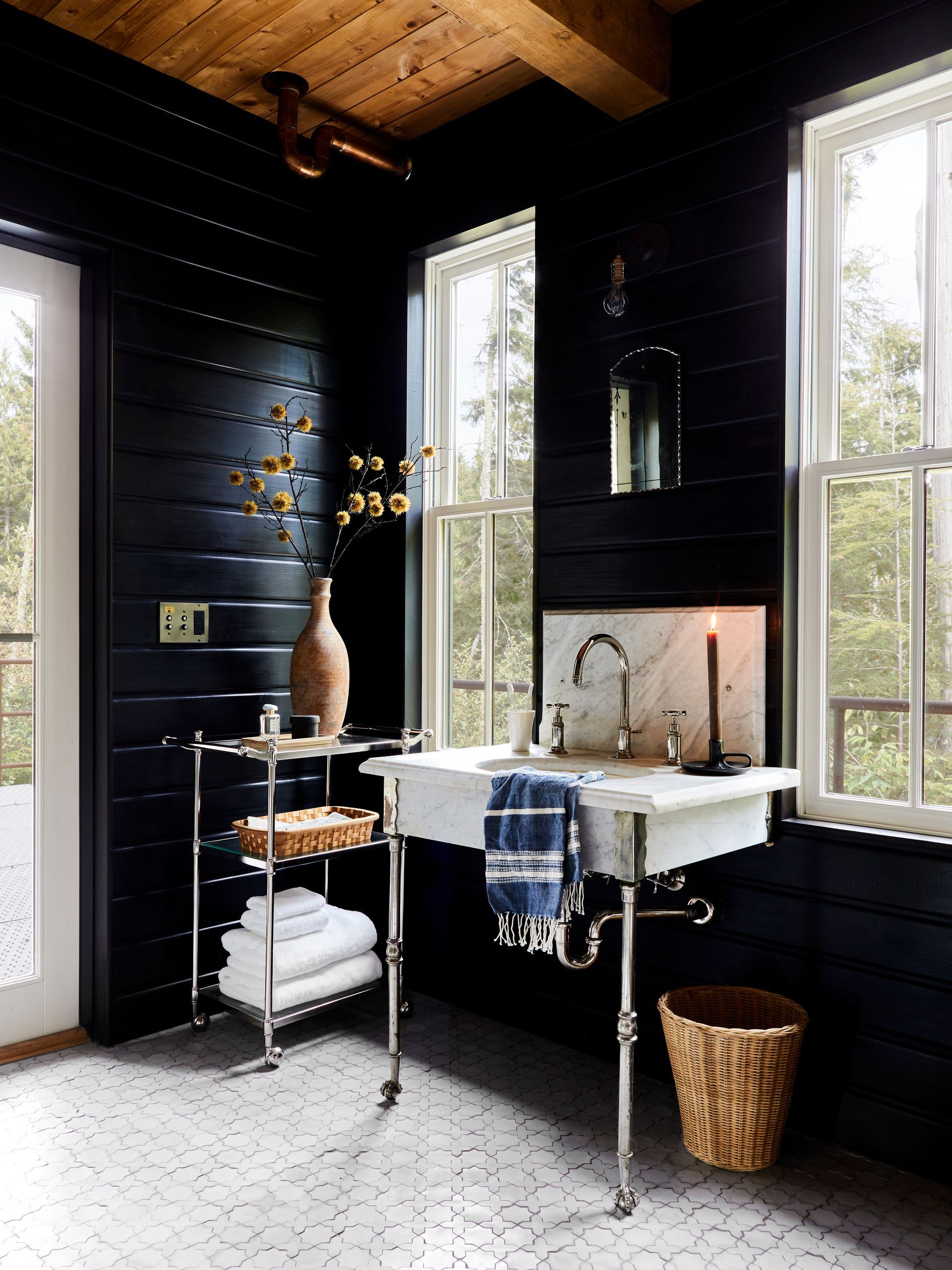 Bathroom with black-stained paneling on walls, star and cross mosaic concrete tile floor and an antique console vanity sink.