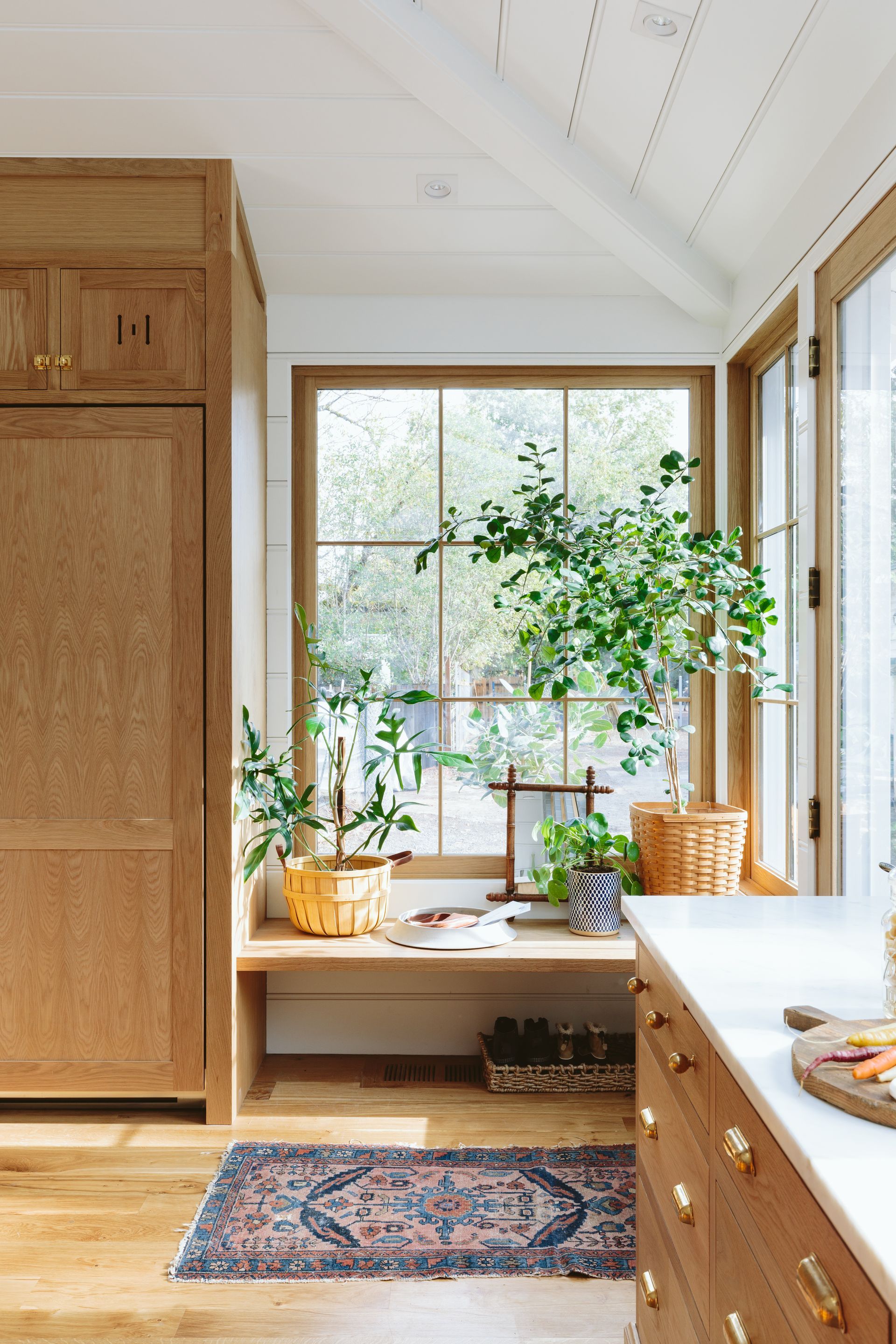 The deep Oak bench at the back entry, surrounded by windows and abutting the built in refrigerator.