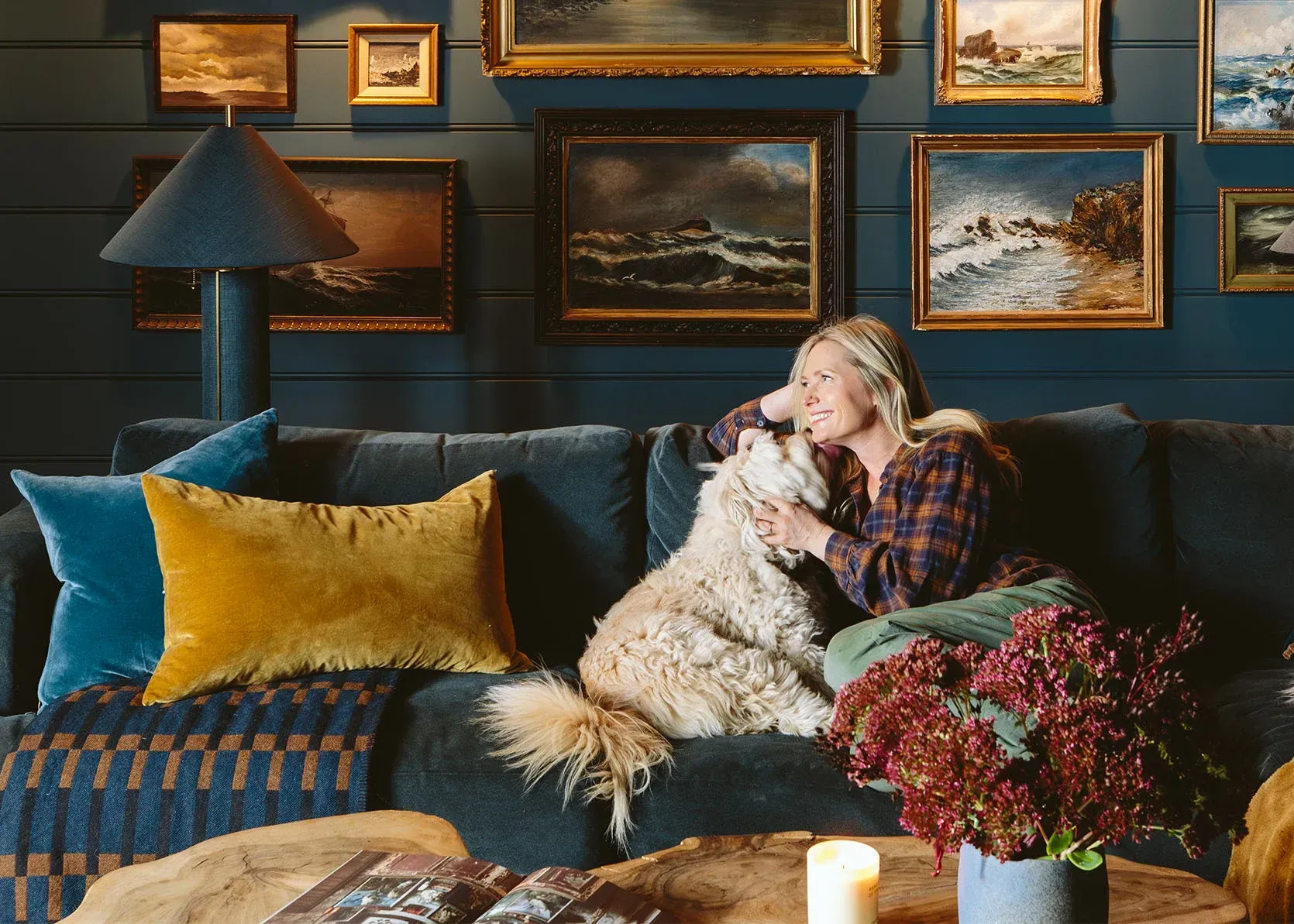 A woman is sitting on a couch with a dog.
