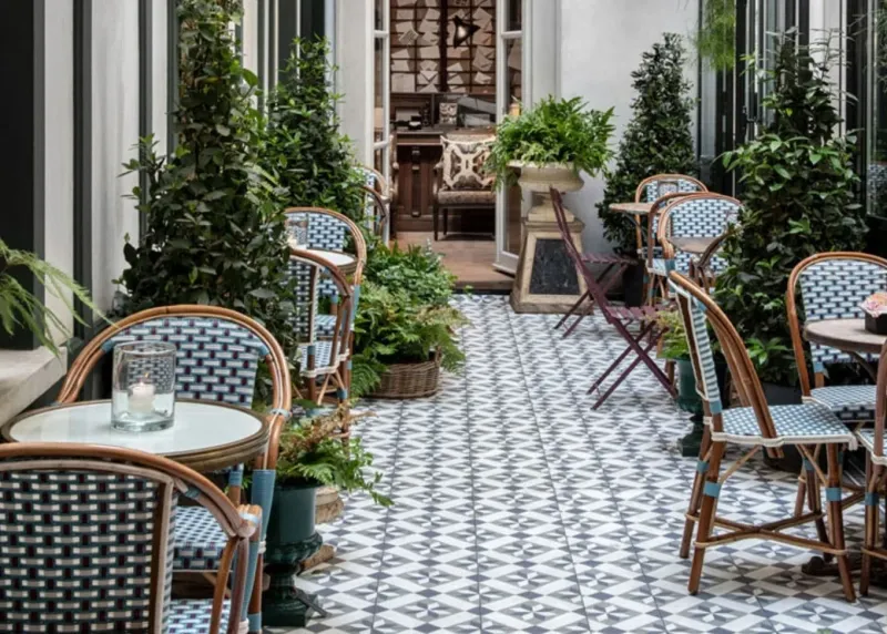A patio with tables and chairs and plants on it.