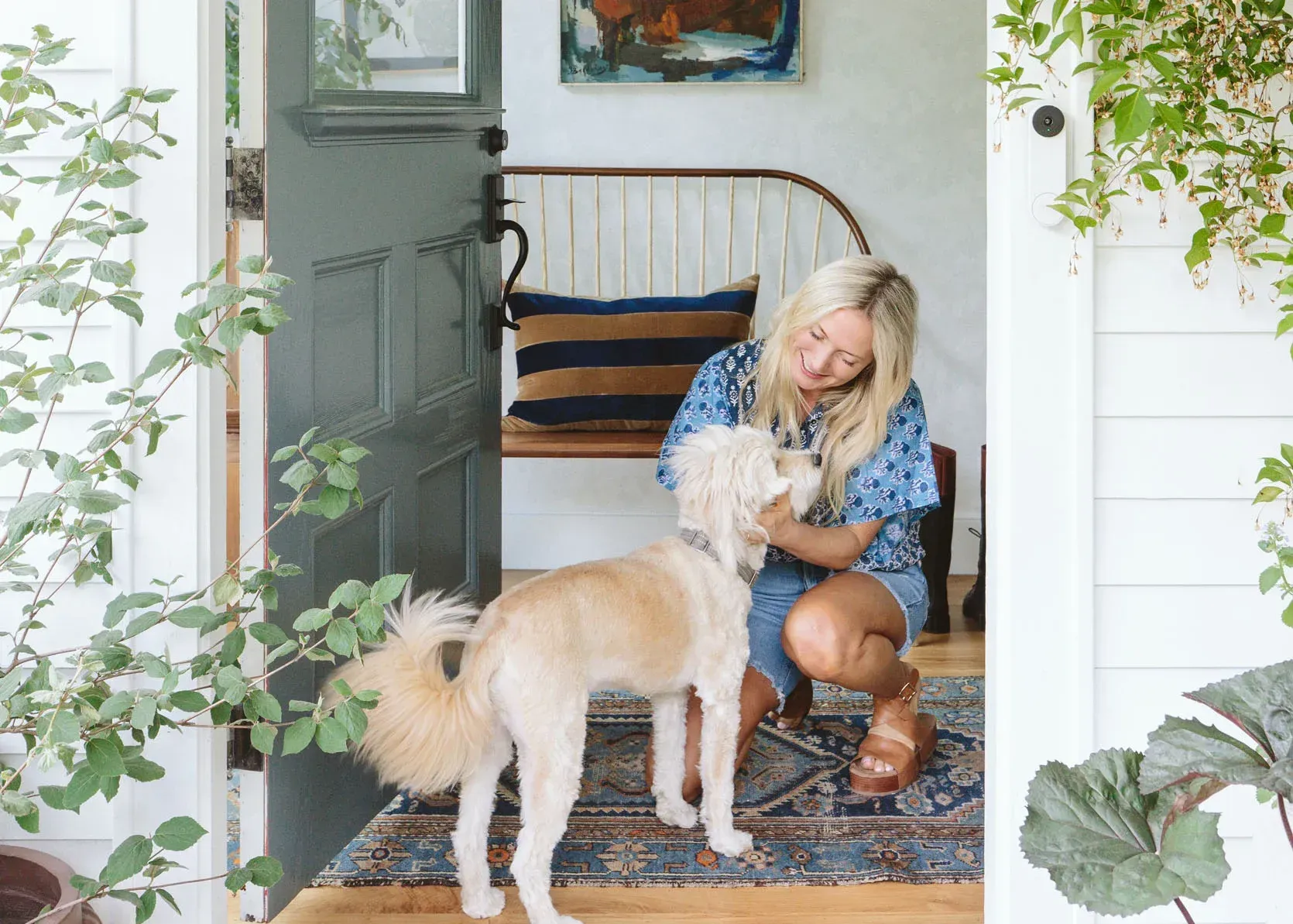 A woman is kneeling down next to a dog in a doorway.