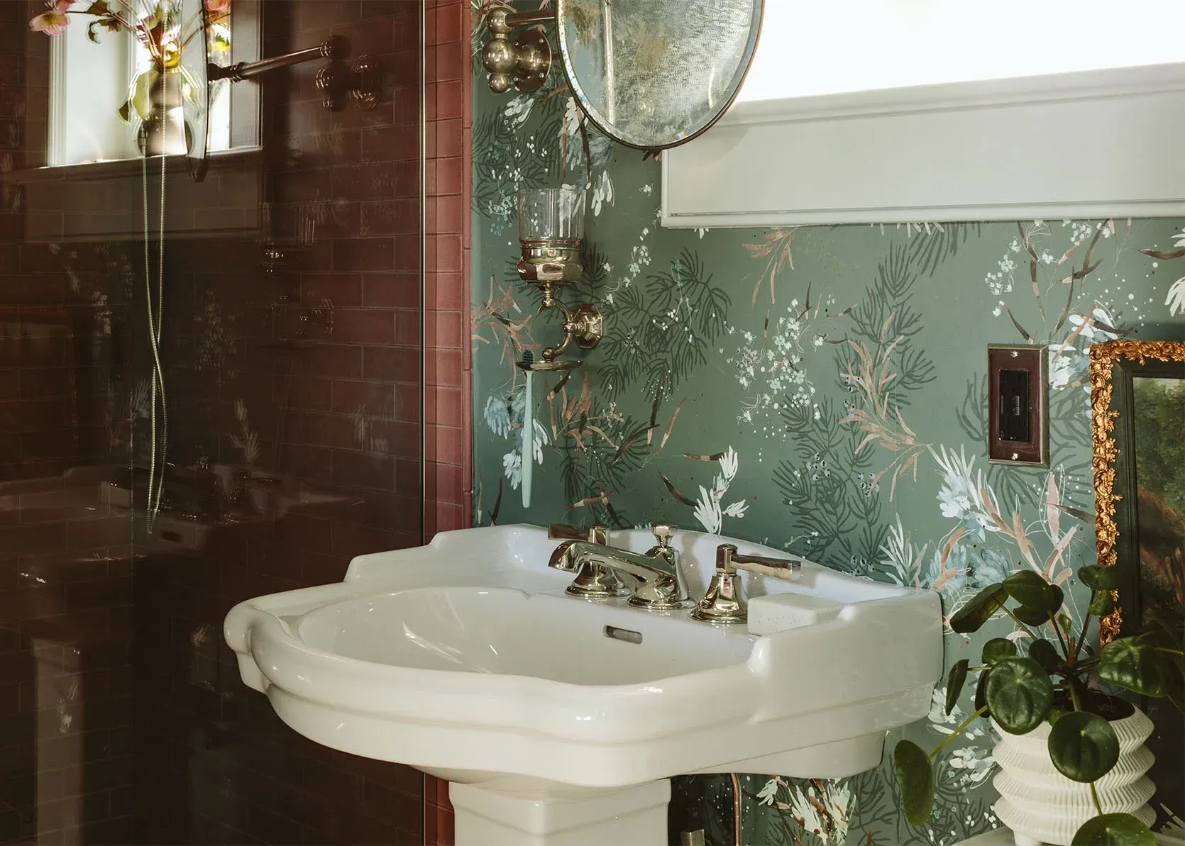 A bathroom with a sink , mirror , and plant.