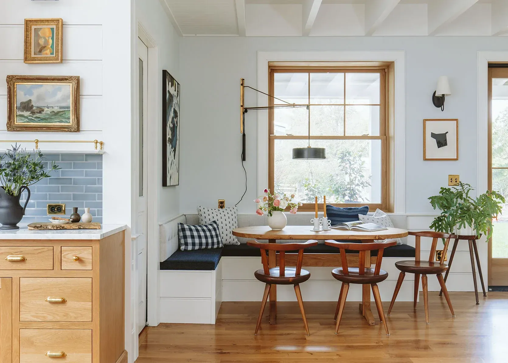 A dining room with a table and chairs in front of a window.