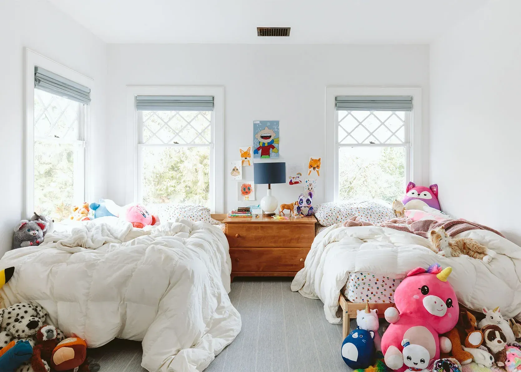 A bedroom with two beds and lots of stuffed animals.