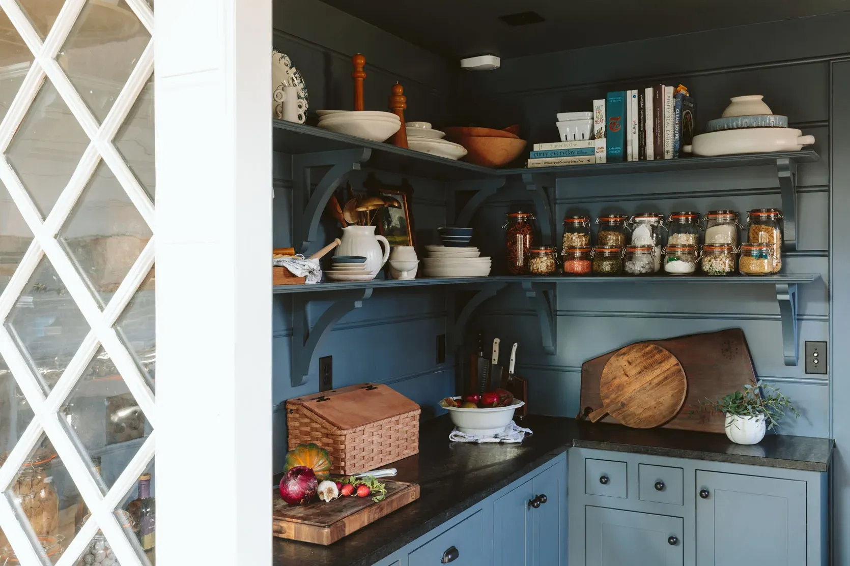A kitchen with blue cabinets and shelves filled with pots and pans.