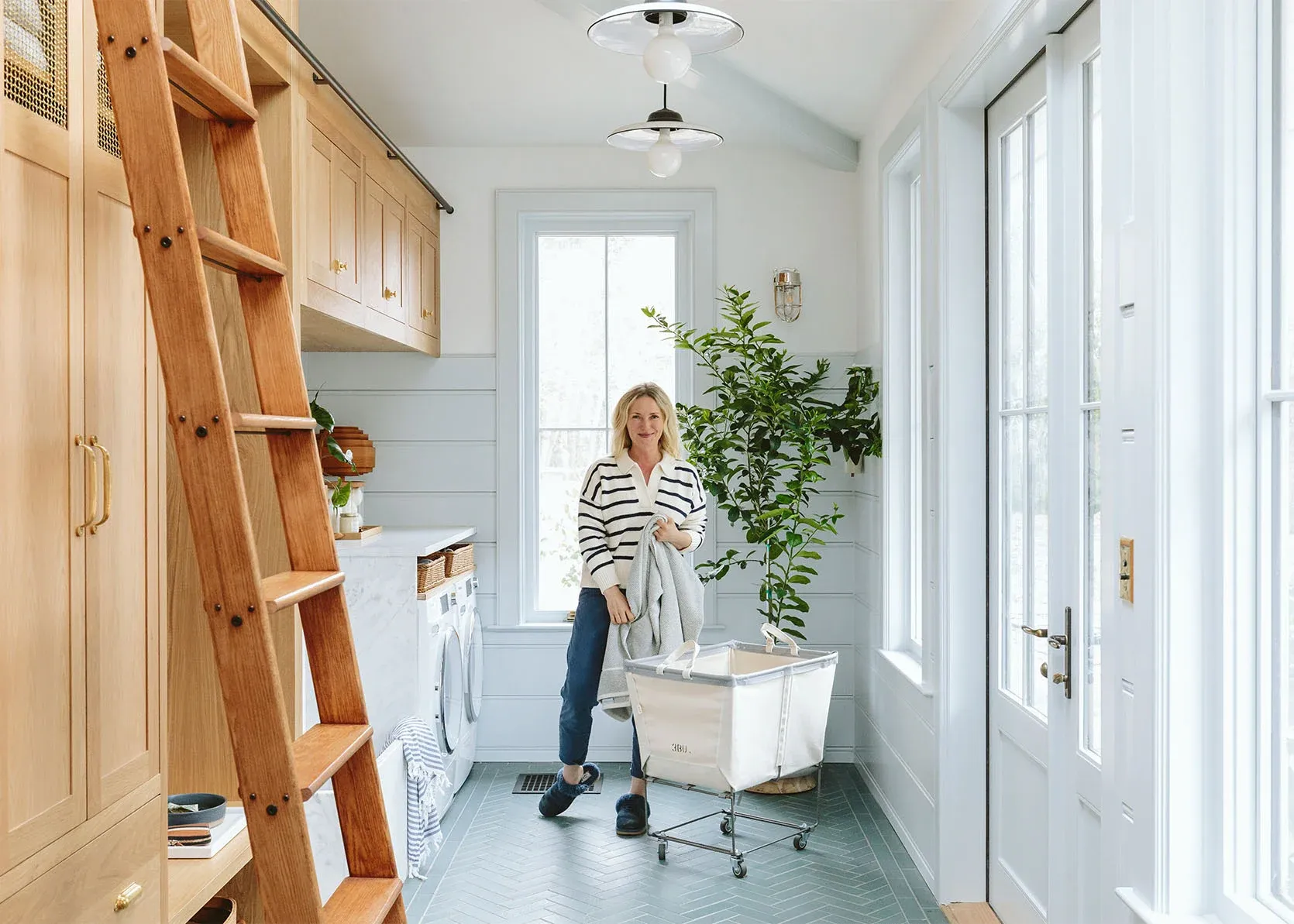 A woman is standing in a laundry room with a ladder.