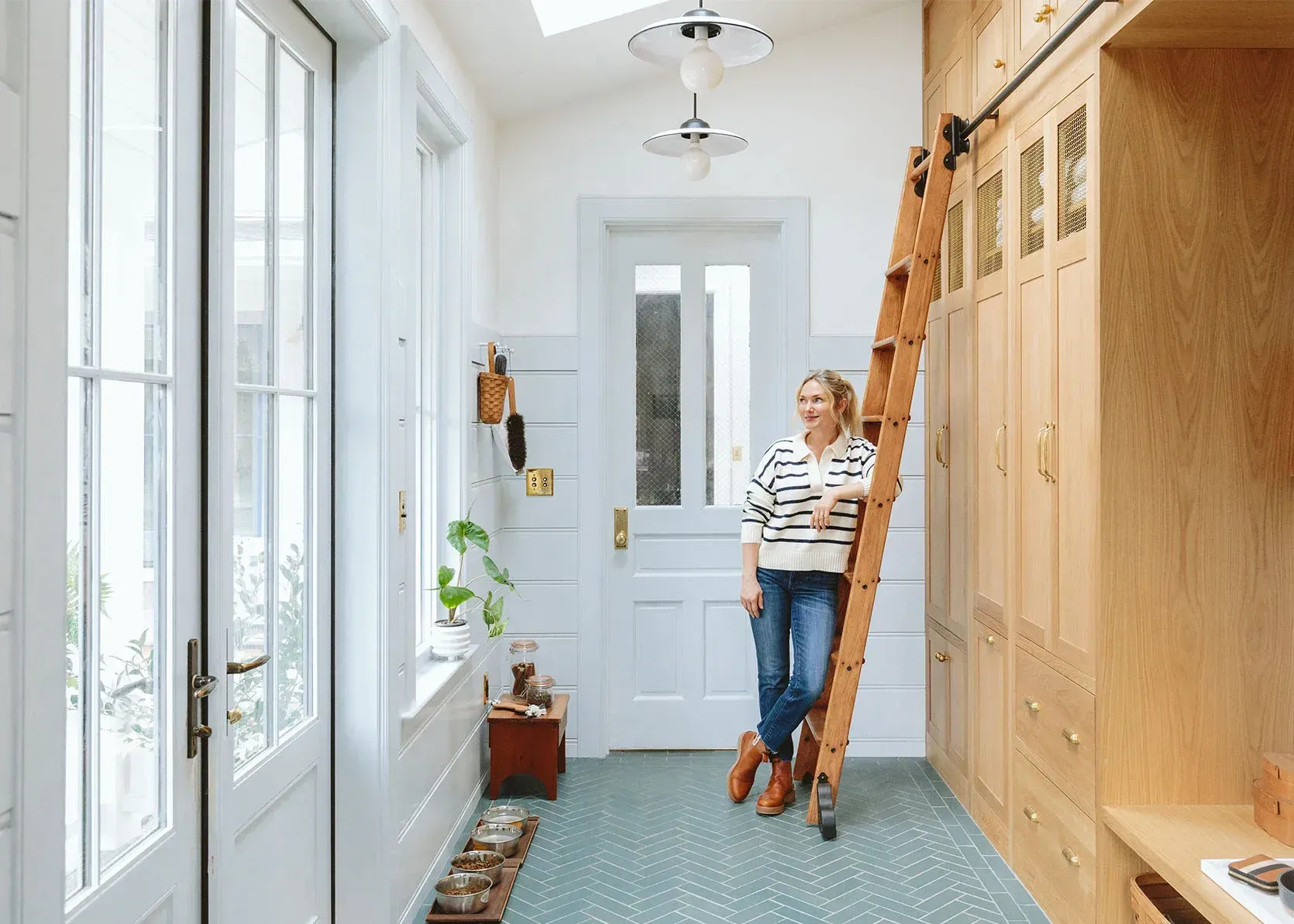 A woman is standing on a wooden ladder in a hallway.