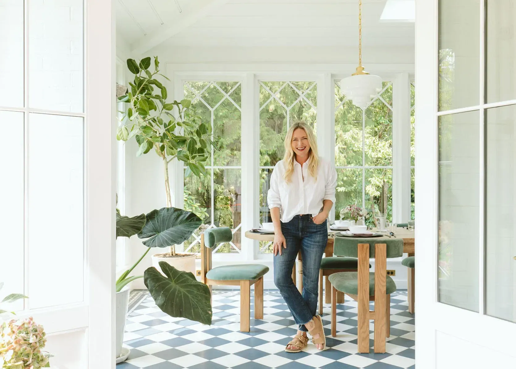 A woman is standing in a dining room next to a table and chairs.